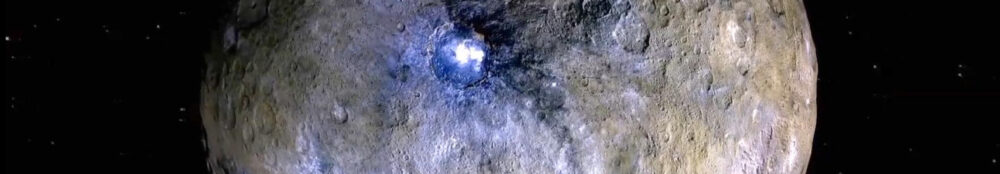 Ceres in Totalansicht, gräulich bis bräunlich mit vielen Kratern, hervor sticht ein heller Fleck im Krater Occator im Mittelpunkt, heller als alles andere