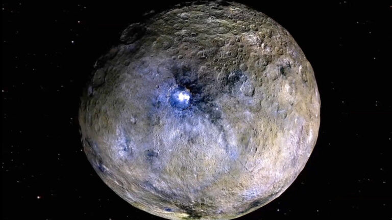 Ceres in Totalansicht, gräulich bis bräunlich mit vielen Kratern, hervor sticht ein heller Fleck im Krater Occator im Mittelpunkt, heller als alles andere