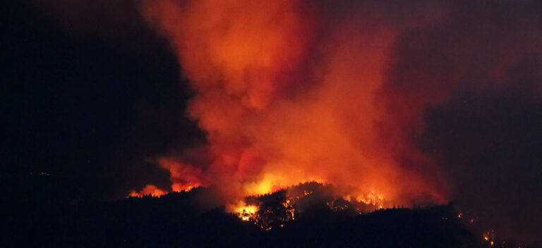 Ein Waldbrand in Kalifornien beleuchtet als helle Pünktchen einen nächtlichen Berghang.