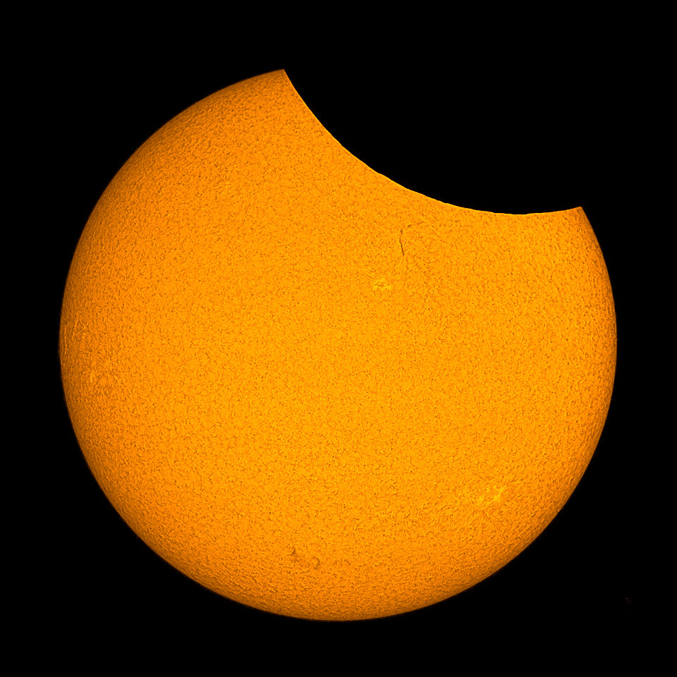 Gelblich eingefärbtes H-alpha-Bild einer partiellen Sonnenfinsternis, bei der am oberen Sonnenrand ca. 10% der Sonnenoberfläche fehlen