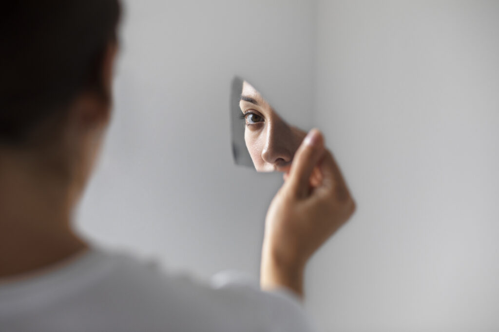 Frau, die sich in einer Spiegelscherbe ansieht