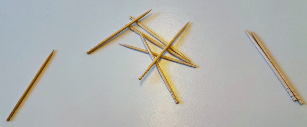Photo of a pile of toothpicks, with one off to the left and two off to the right