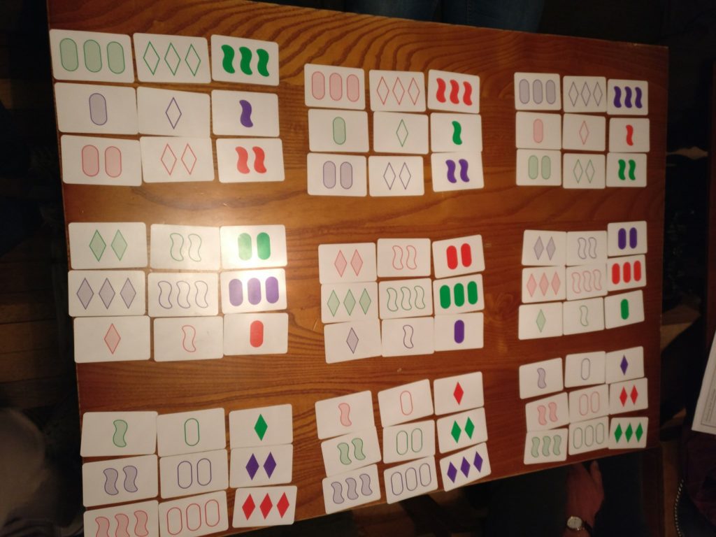 81 SET cards, arranged in a hypercube on the table in the pub