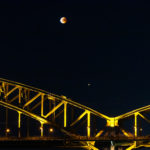 Mondfinsternis in Köln über einer Eisenbahnbrücke