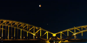 Mondfinsternis in Köln über einer Eisenbahnbrücke