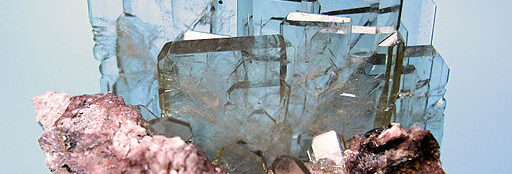 Gruppe von durchsichtigen, farblosen und tafeligen Barytkristallen auf Muttergestein. Gesamtgröße: 56 mm x 53 mm. Großer Kristall: 22 mm breit, 3 mm dick. Gewicht: 74. Fundort: Cerro Warihuyn (Huarihuyn), Miraflores, Provinz Huamalies, Department Huanuco, Peru. Carlesmillan (https://commons.wikimedia.org/wiki/File:6158M-barite2.jpg), „6158M-barite2“, https://creativecommons.org/licenses/by-sa/3.0/legalcode