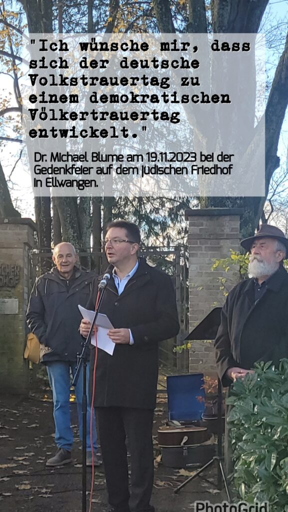 Dr. Michael Blume mit zwei Gedenkenden am jüdischen Friedhof in Ellwangen. Darüber ein Zitat aus seiner Rede: "Ich wünsche mir, dass sich der deutsche Volkstrauertag zu einem demokratischen Völkertrauertag entwickelt." Link zum pdf der Rede
