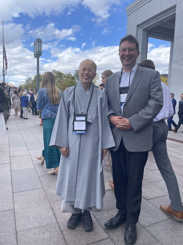 Eine buddhistische Nonne und ein evangelischer Religionswissenschaftler, beide aus Deutschland, lächeln in die Oktobersonne von Salt Lake City 2023.